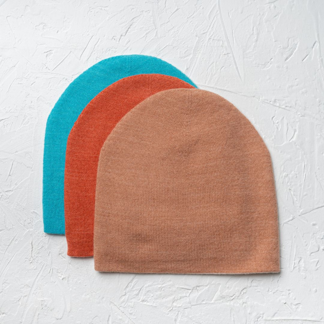 3 cashmere beanies stacked on top of each other in cork, burnt sienna, and baltic colors