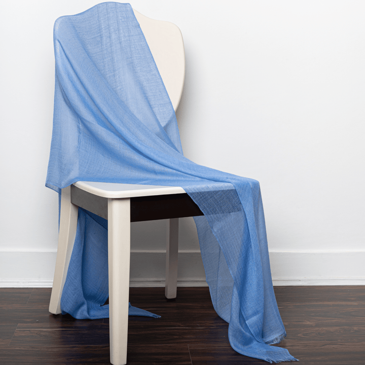Blue Tint 100% Cashmere Ring Scarf draped like a sash over a white-painted wooden chair with white wall background on dark brown wood floor#color_blue-tint