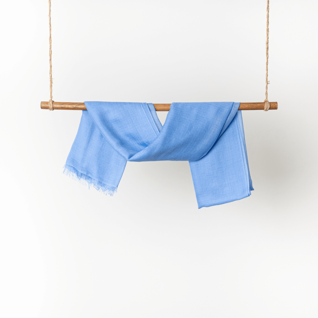 Blue Tint 100% Cashmere Ring Scarf hanging on a wooden dowel rod wrapped in twine on both ends#color_blue-tint