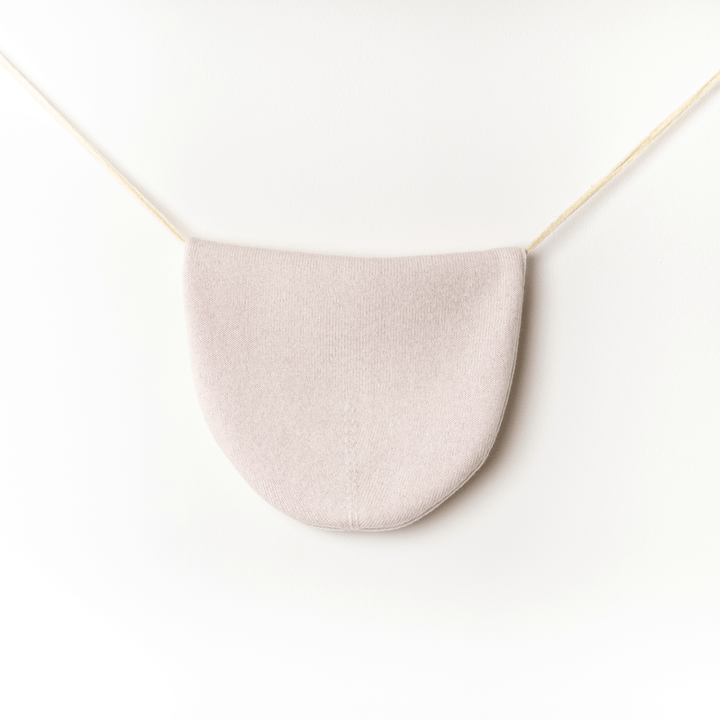 Reversible 100% Cashmere Beanie in Tender Touch(Pink) and Blanc de Blanc(White) hung on a twine string against a white wall #color_tender-touch-and-blanc-de-blanc