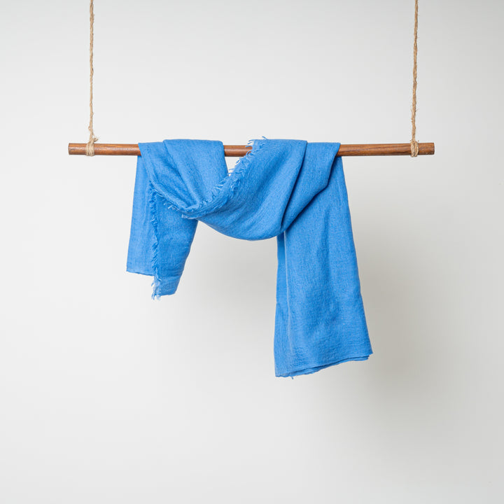 Blue 100% Cashmere Felted Shawl hanging on a wooden dowel rod wrapped in twine on both ends #color_blue