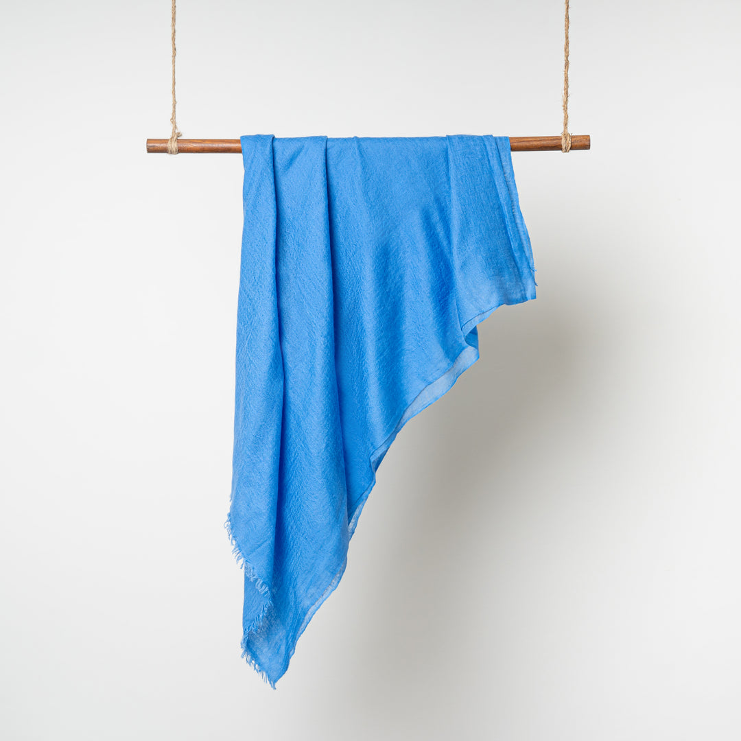 Blue 100% Cashmere Felted Shawl hanging on a wooden dowel rod wrapped in twine on both ends #color_blue