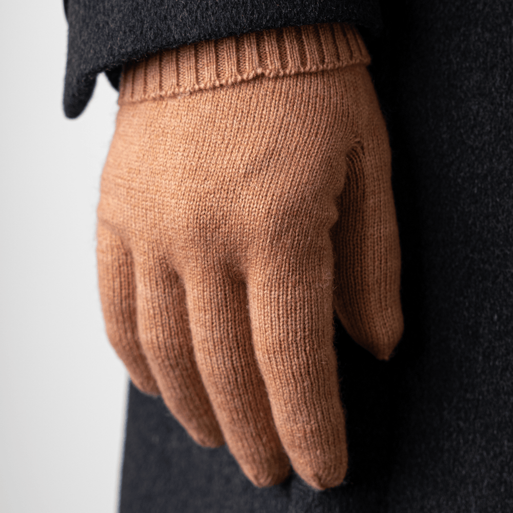 Cork 100% Cashmere Gloves worn on the right hand held down by the side of a body wearing a dark grey trench coat#color_cork