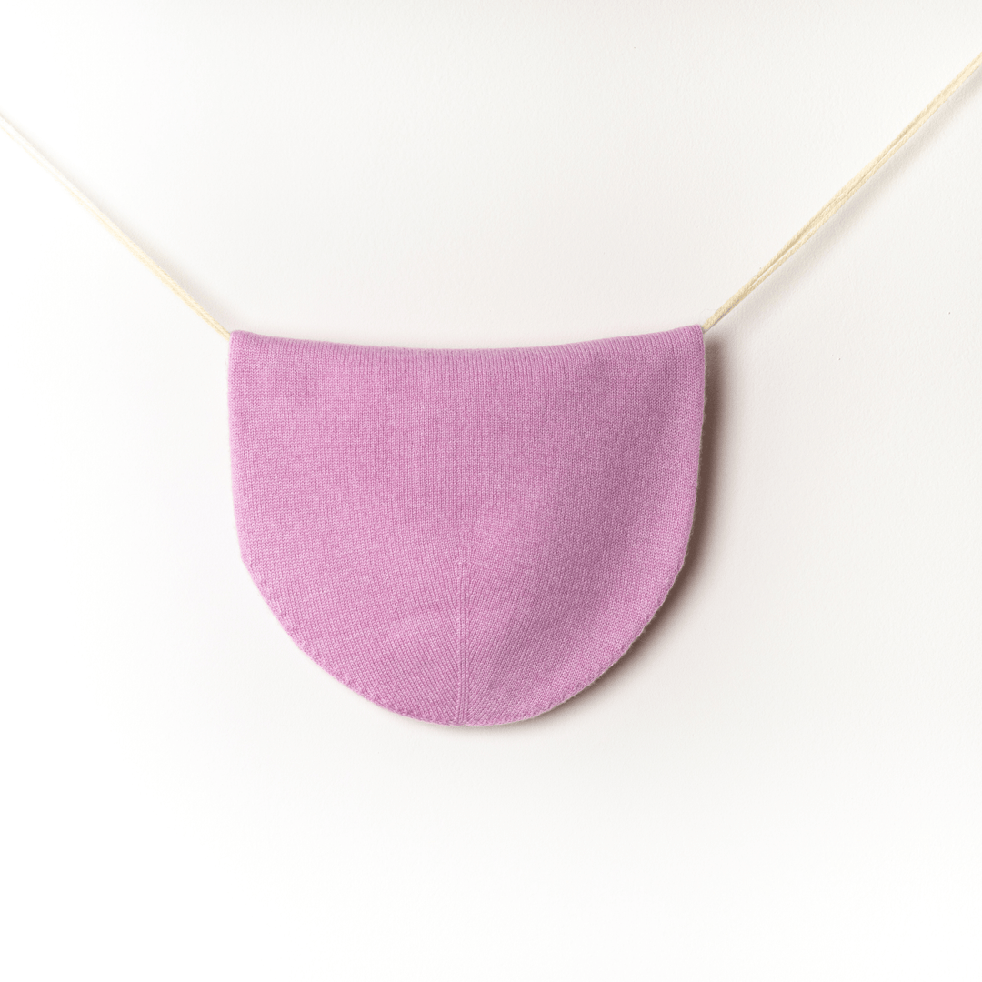 Pink side of Reversible 100% Cashmere Beanie in Tender Touch(Pink) and Blanc de Blanc(White) hung against a white wall#color_tender-touch-and-blanc-de-blanc